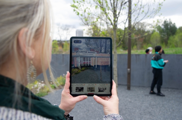 Person holding iPad with augmented reality software that recreates events that happened over 8 months in the 1960s, on a site that is now part of the Georgia Tech campus.