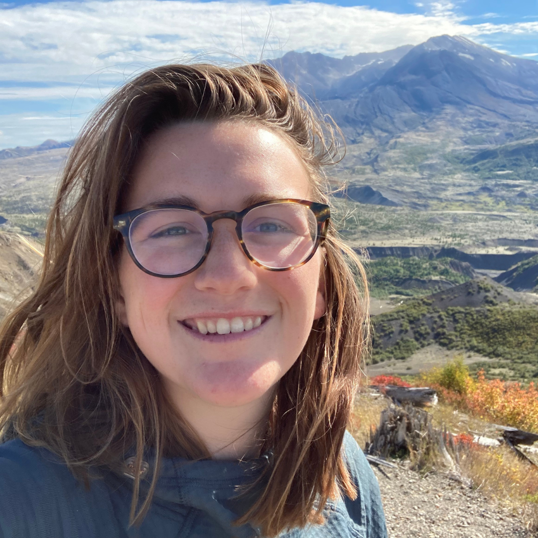 Ellie smiling in a selfie in front of an expansive mountain view