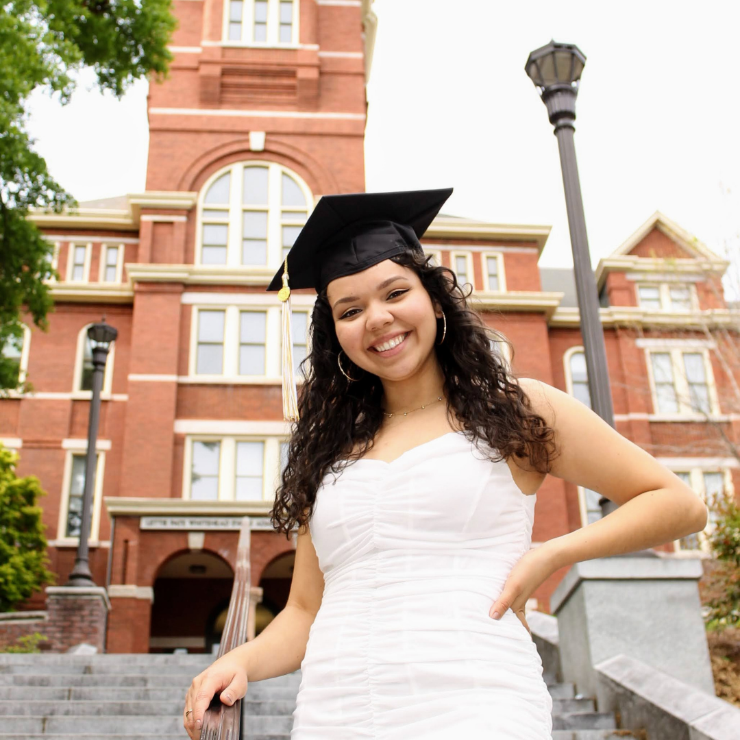 Kim posing in her graduation cap on the stairs in front of tech tower 