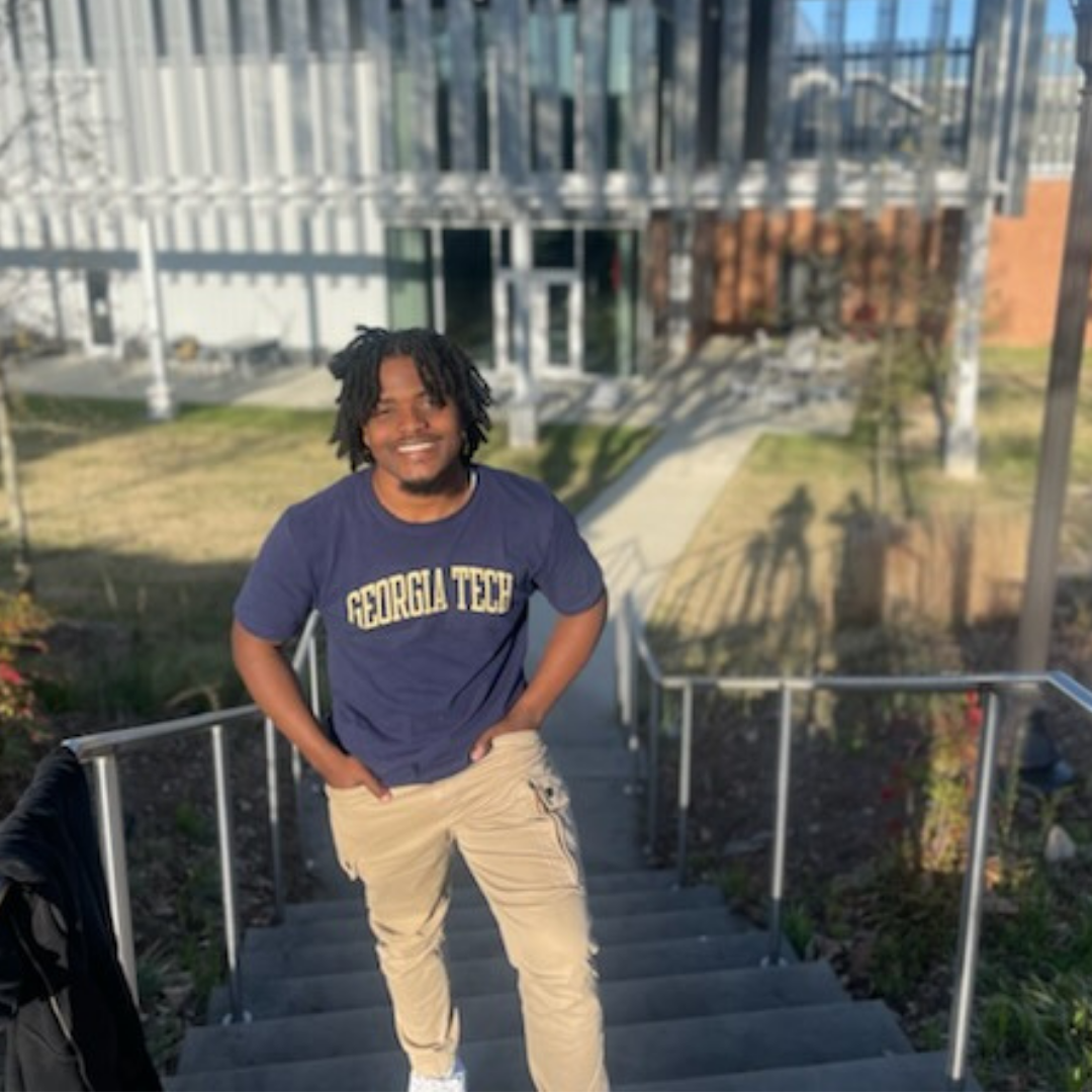 Micah posing on the stairs at Georgia Tech in a GT shirt